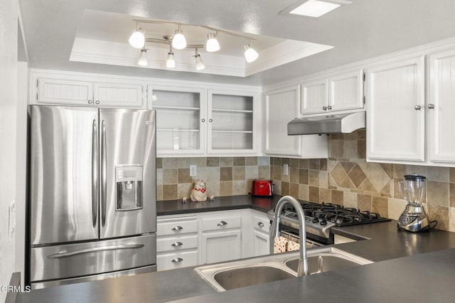 kitchen featuring stainless steel refrigerator with ice dispenser, dark countertops, a sink, under cabinet range hood, and a tray ceiling