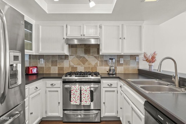 kitchen with white cabinets, appliances with stainless steel finishes, a sink, decorative backsplash, and under cabinet range hood