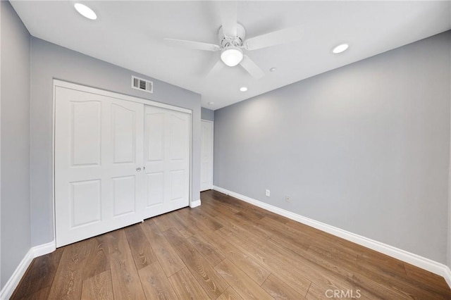 unfurnished bedroom featuring baseboards, wood finished floors, and visible vents