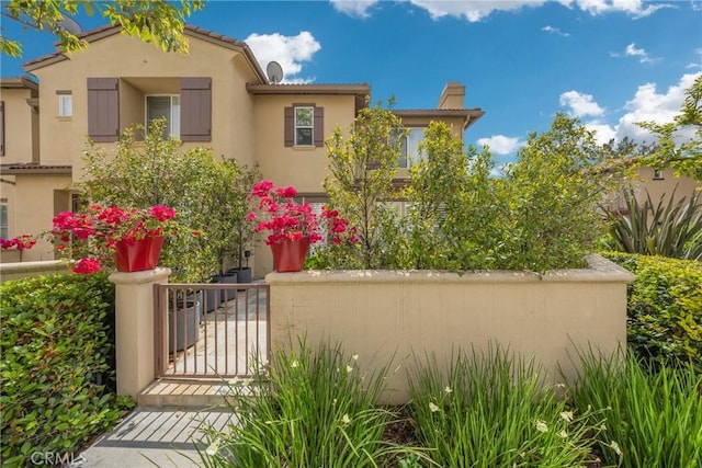 view of front facade featuring a gate, stucco siding, and fence