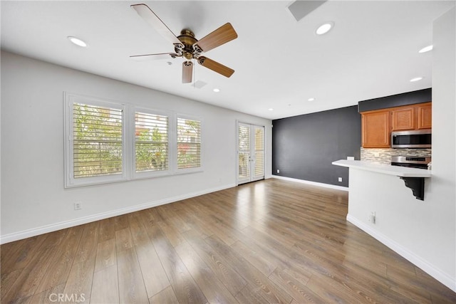 unfurnished living room featuring baseboards, recessed lighting, ceiling fan, and wood finished floors