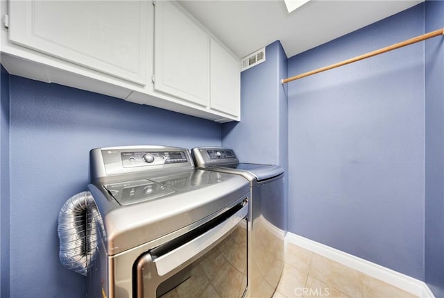 clothes washing area with visible vents, washing machine and dryer, cabinet space, light tile patterned floors, and baseboards