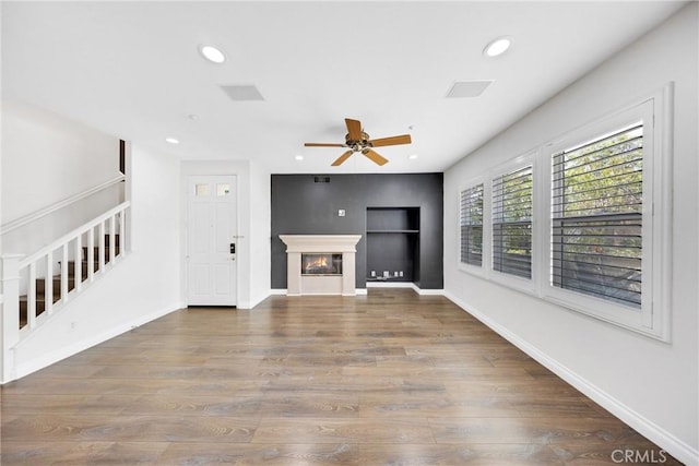 unfurnished living room featuring a ceiling fan, recessed lighting, wood finished floors, and stairs