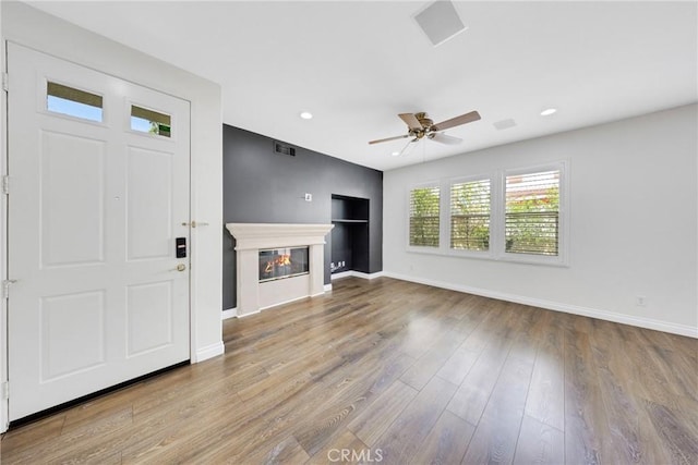 unfurnished living room featuring baseboards, ceiling fan, visible vents, and wood finished floors
