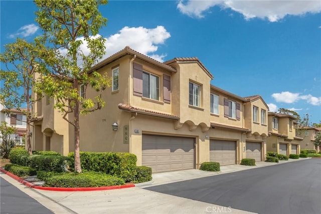 view of front of home with a garage, stucco siding, a tiled roof, and a residential view