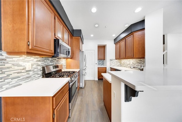 kitchen featuring light wood-style floors, recessed lighting, light countertops, tasteful backsplash, and stainless steel appliances