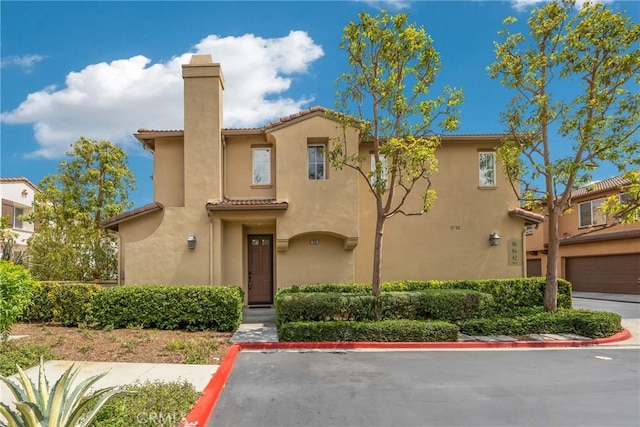 mediterranean / spanish home with a chimney, a tile roof, and stucco siding