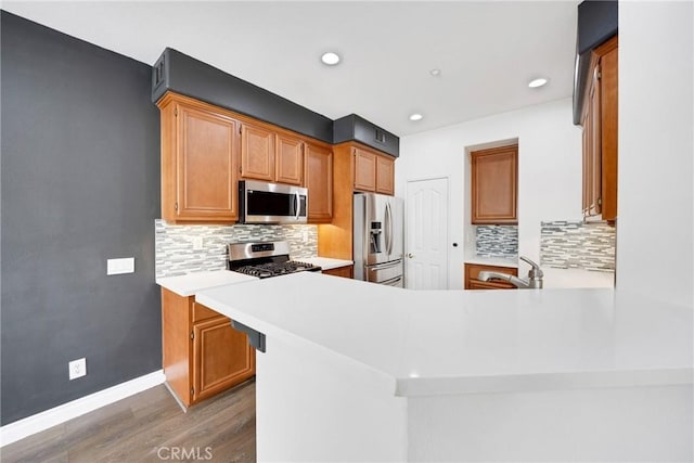 kitchen with light wood-type flooring, light countertops, decorative backsplash, and stainless steel appliances