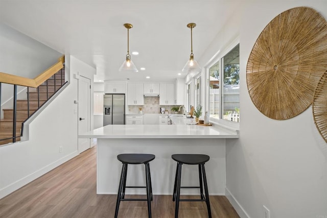 223 Cottingham Ct, Oceanside, CA 92054 - kitchen featuring stainless steel refrigerator with ice dispenser, a peninsula, white cabinets, wood finished floors, and recessed lighting