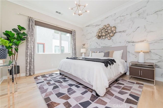 bedroom featuring an inviting chandelier, wood finished floors, visible vents, and baseboards