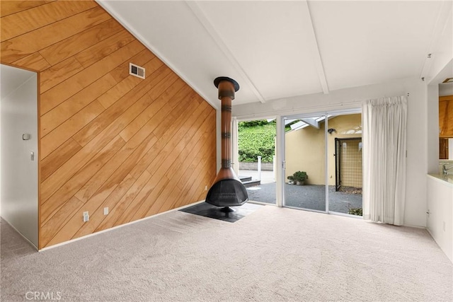unfurnished living room with vaulted ceiling with beams, carpet flooring, and wood walls