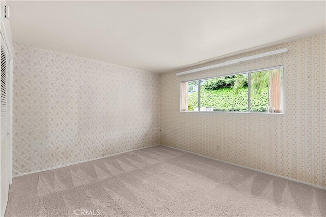 spare room featuring light carpet and wallpapered walls