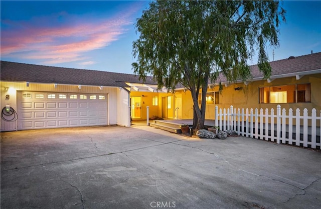 ranch-style house featuring driveway, fence private yard, and a garage