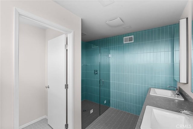 full bathroom with a sink, tile patterned floors, a shower stall, and visible vents