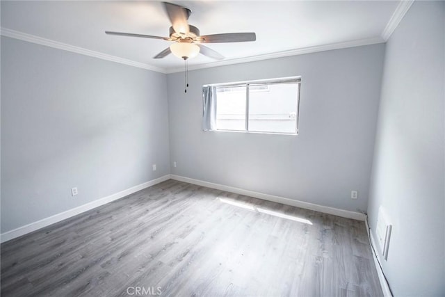 spare room featuring a ceiling fan, baseboards, ornamental molding, and wood finished floors