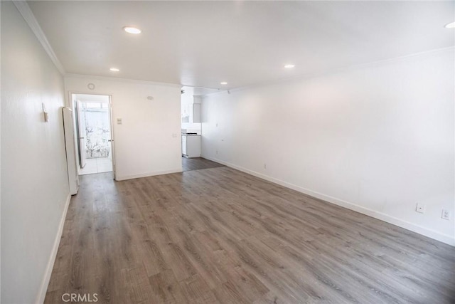 unfurnished living room with crown molding, baseboards, and wood finished floors