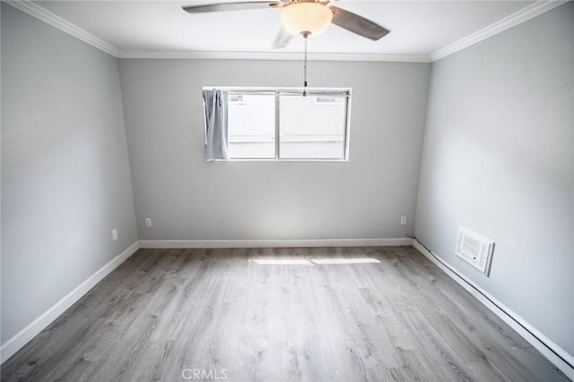spare room with ceiling fan, visible vents, crown molding, wood finished floors, and baseboards