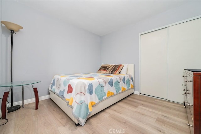bedroom with baseboards, wood finished floors, and a closet