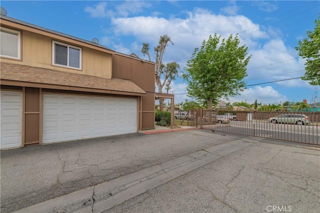 garage with fence, a gate, and driveway