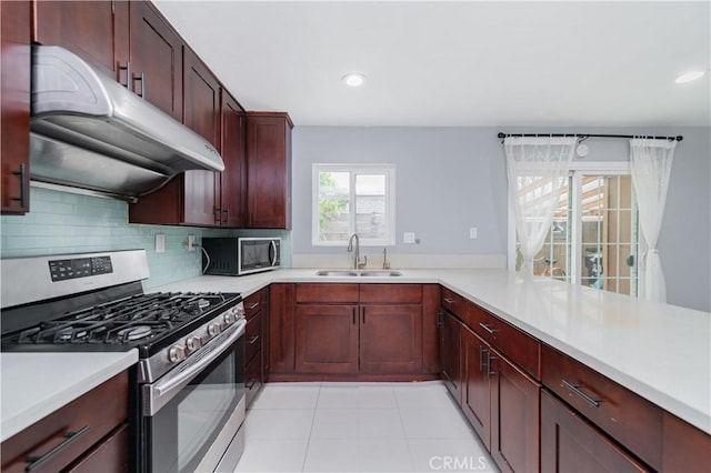 kitchen featuring a sink, light countertops, stainless steel appliances, decorative backsplash, and under cabinet range hood