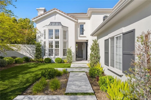 3 Bridgeport Rd, Newport Coast, CA 92657 - view of exterior entry with a lawn, stucco siding, a chimney, and a tile roof