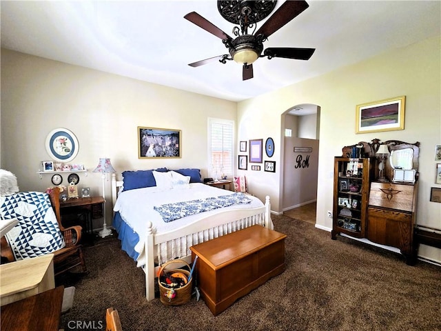 carpeted bedroom featuring baseboards, arched walkways, and a ceiling fan