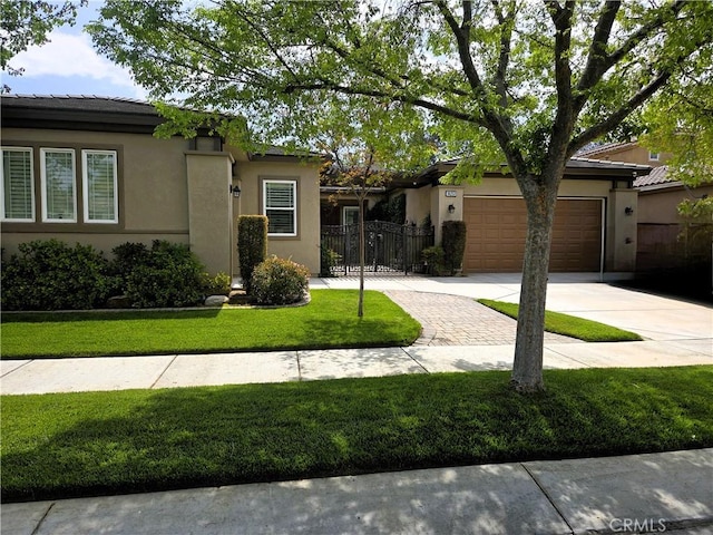 view of front of house featuring driveway, a front yard, a garage, fence, and stucco siding