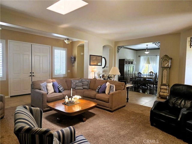 living area featuring arched walkways, light carpet, and light tile patterned floors