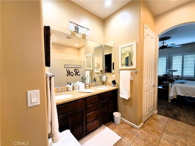 ensuite bathroom featuring connected bathroom, double vanity, ceiling fan, and a sink