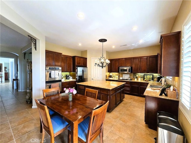 kitchen featuring a center island, an inviting chandelier, light tile patterned flooring, and stainless steel appliances