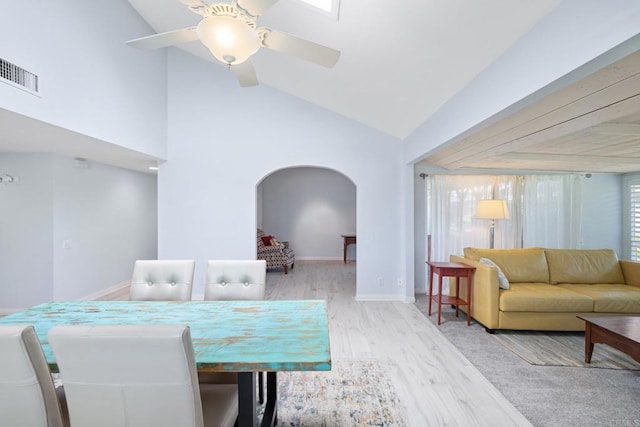 dining space with arched walkways, a ceiling fan, baseboards, wood finished floors, and visible vents