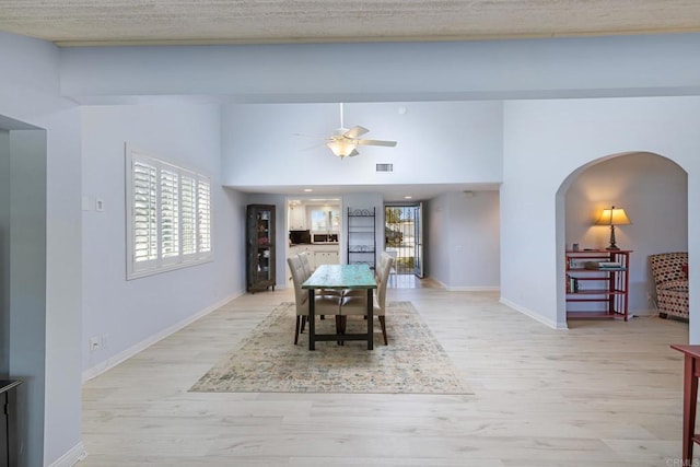 dining space with visible vents, a ceiling fan, arched walkways, and light wood-type flooring