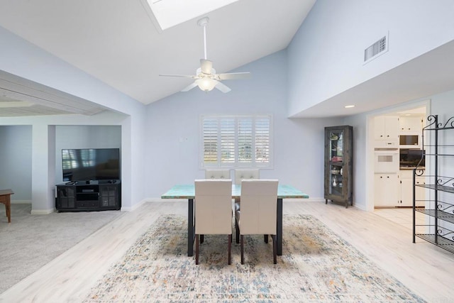 dining space with ceiling fan, high vaulted ceiling, light wood-style flooring, baseboards, and visible vents
