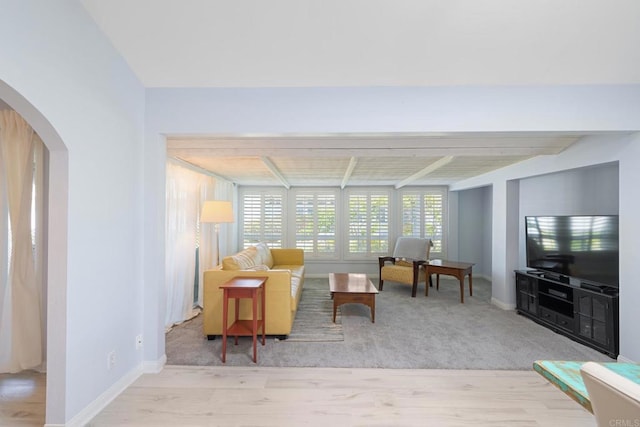 living area with wood finished floors, arched walkways, and beam ceiling
