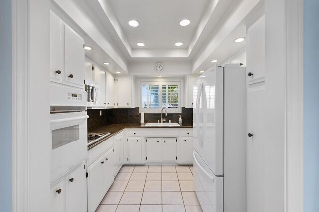 3685 Vista Campana N Unit 61, Oceanside, CA 92057 - kitchen featuring white appliances, dark countertops, decorative backsplash, light tile patterned flooring, and white cabinetry