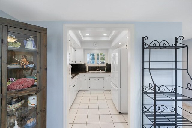 3685 Vista Campana N Unit 61, Oceanside, CA 92057 - kitchen featuring freestanding refrigerator, light tile patterned flooring, white cabinets, dark countertops, and a raised ceiling