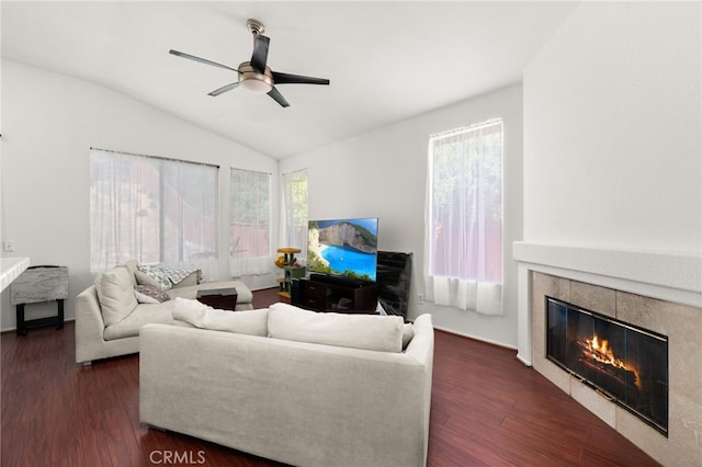 living room with dark wood-type flooring, ceiling fan, vaulted ceiling, and a fireplace