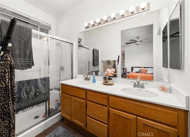 ensuite bathroom with a sink, ceiling fan, a shower stall, and double vanity