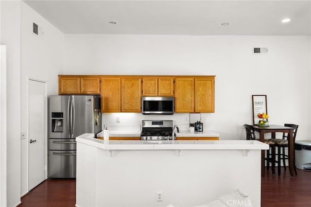 kitchen featuring appliances with stainless steel finishes, tile counters, dark wood-style flooring, and visible vents