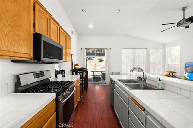 kitchen featuring a sink, tile countertops, a ceiling fan, appliances with stainless steel finishes, and vaulted ceiling