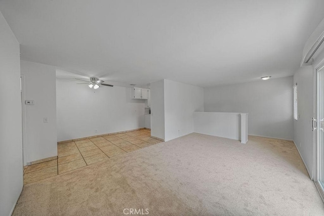 empty room featuring a ceiling fan, light tile patterned flooring, and light carpet