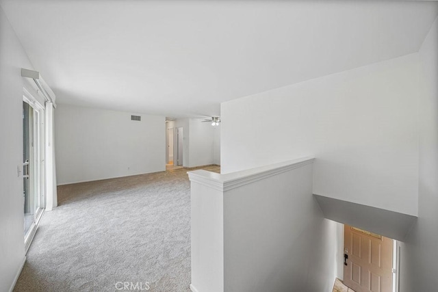 interior space with visible vents, plenty of natural light, an upstairs landing, and light colored carpet