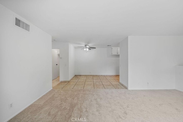 empty room featuring light colored carpet, a ceiling fan, visible vents, and baseboards