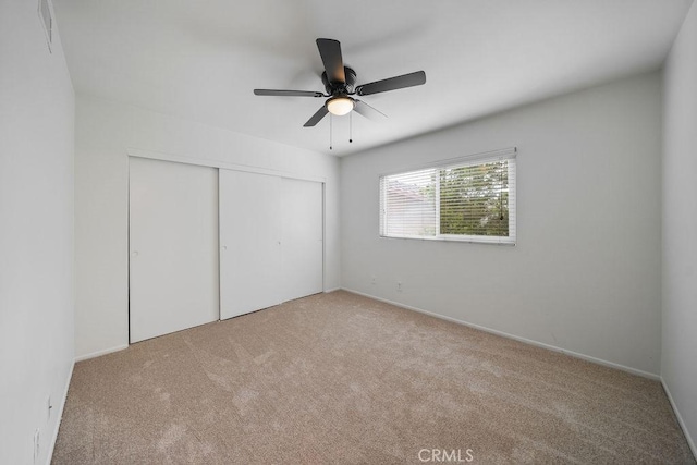 unfurnished bedroom featuring carpet floors, a ceiling fan, visible vents, and a closet