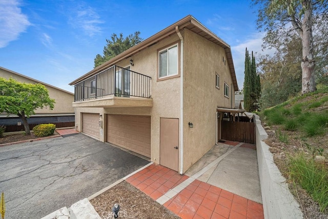 view of home's exterior with a garage, stucco siding, driveway, and a balcony
