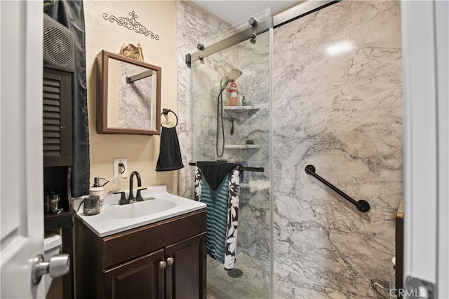 full bath featuring a marble finish shower and vanity