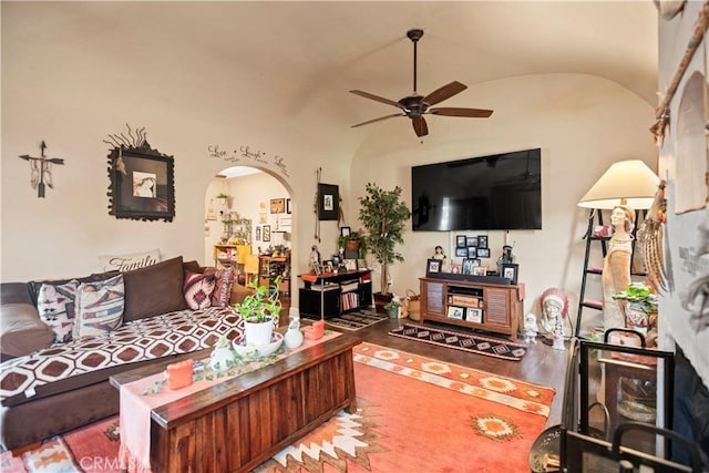 living area featuring arched walkways, a ceiling fan, vaulted ceiling, and wood finished floors
