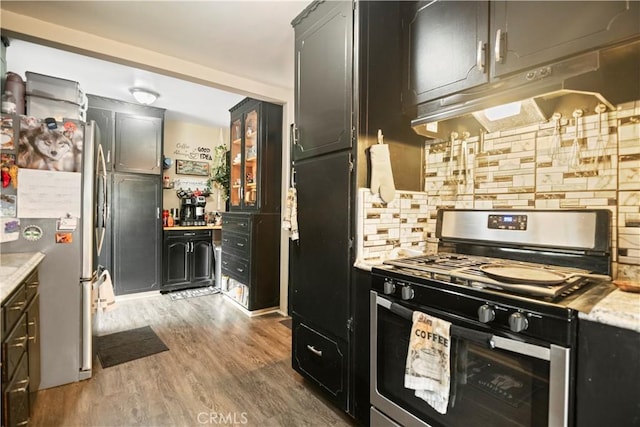 kitchen with backsplash, appliances with stainless steel finishes, light countertops, light wood finished floors, and under cabinet range hood