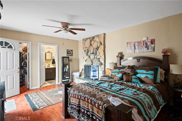 bedroom with a sink, light wood finished floors, ensuite bath, a ceiling fan, and a spacious closet
