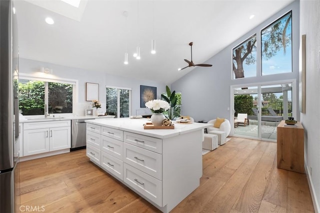 8 Recodo, Irvine, CA 92620 - kitchen featuring appliances with stainless steel finishes, white cabinetry, light wood-style flooring, open floor plan, and a kitchen island
